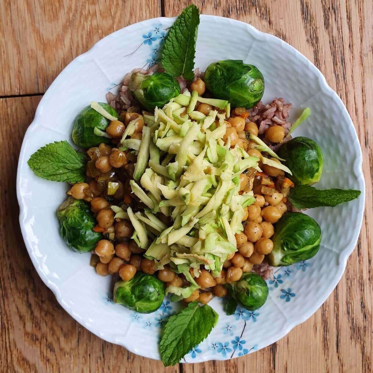 A bowl of food with sprouts and beans on it.