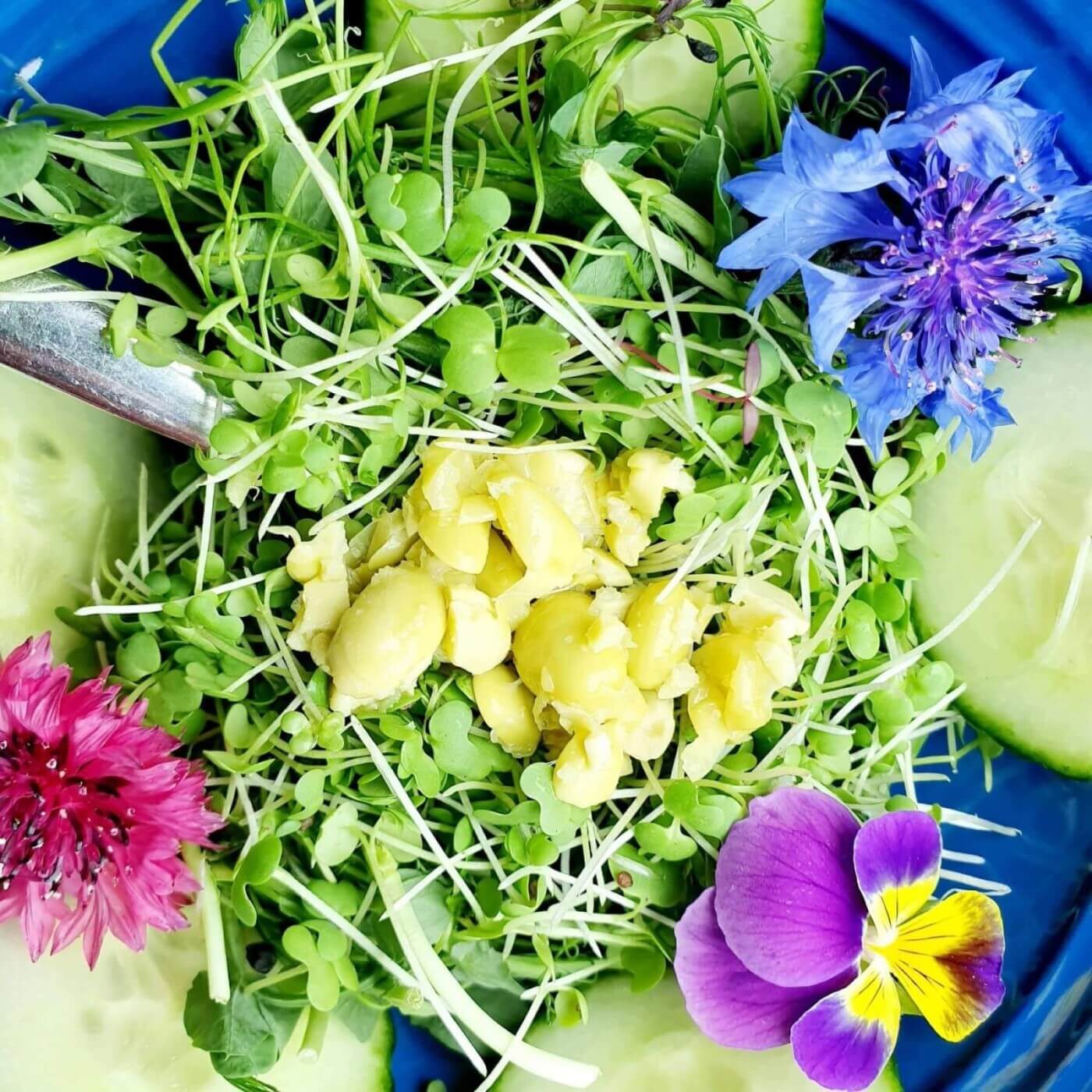 A blue plate topped with salad and flowers.