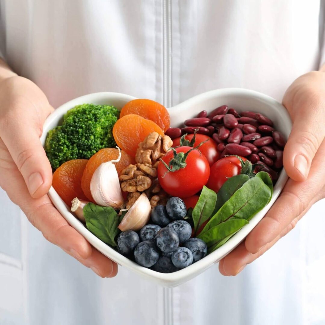 A person holding a bowl of food in the shape of a heart.